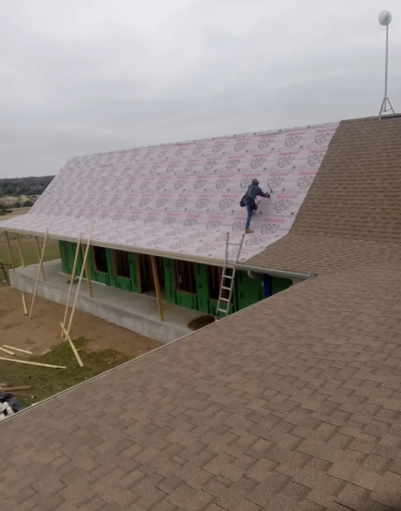 Worker preparing underlayment for a metal roof installation in Van Wert